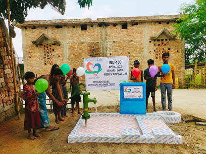 Children playing with balloons near a water pump and board in a rural setting